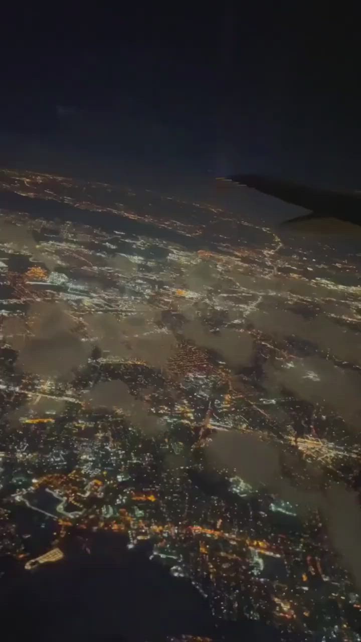 This may contain: an aerial view of the city lights at night taken from an airplane window in flight