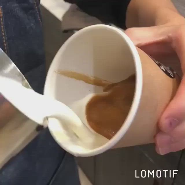 This may contain: a person is holding a cup of coffee and pouring it into the foamy liquid