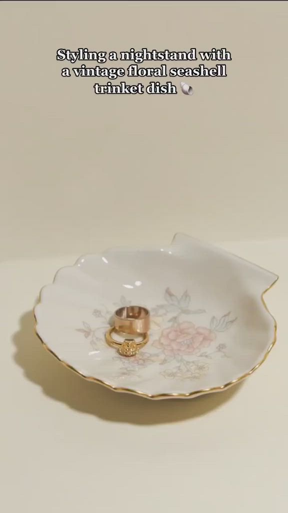 This may contain: two gold wedding rings sitting in a flowered porcelain dish with the words, i'm getting married