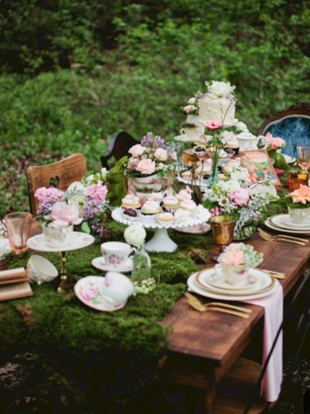 This may contain: the table is covered in moss and has plates, cups, and saucers on it