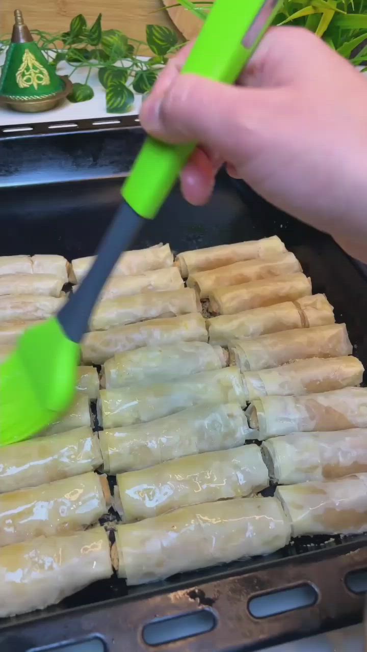 This may contain: a person using a green spatula to stir up food on top of a grill