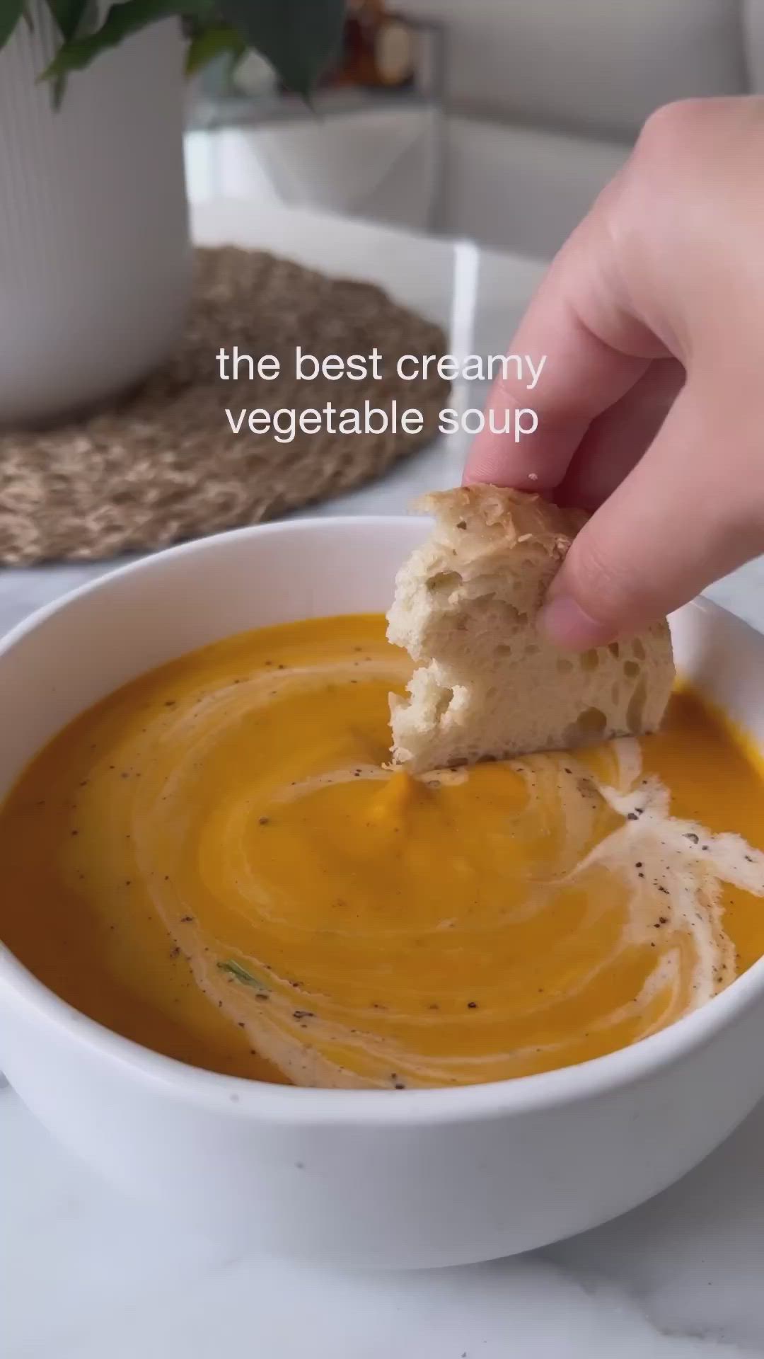 This may contain: a hand dipping a piece of bread into a bowl of soup with the words, the best creamy vegetable soup for more recipes link in my blog