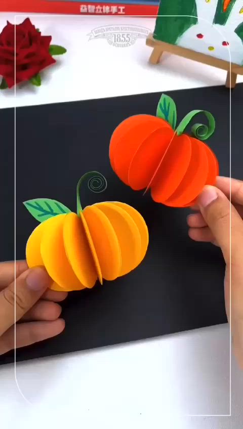 This may contain: two paper pumpkins being cut out with scissors