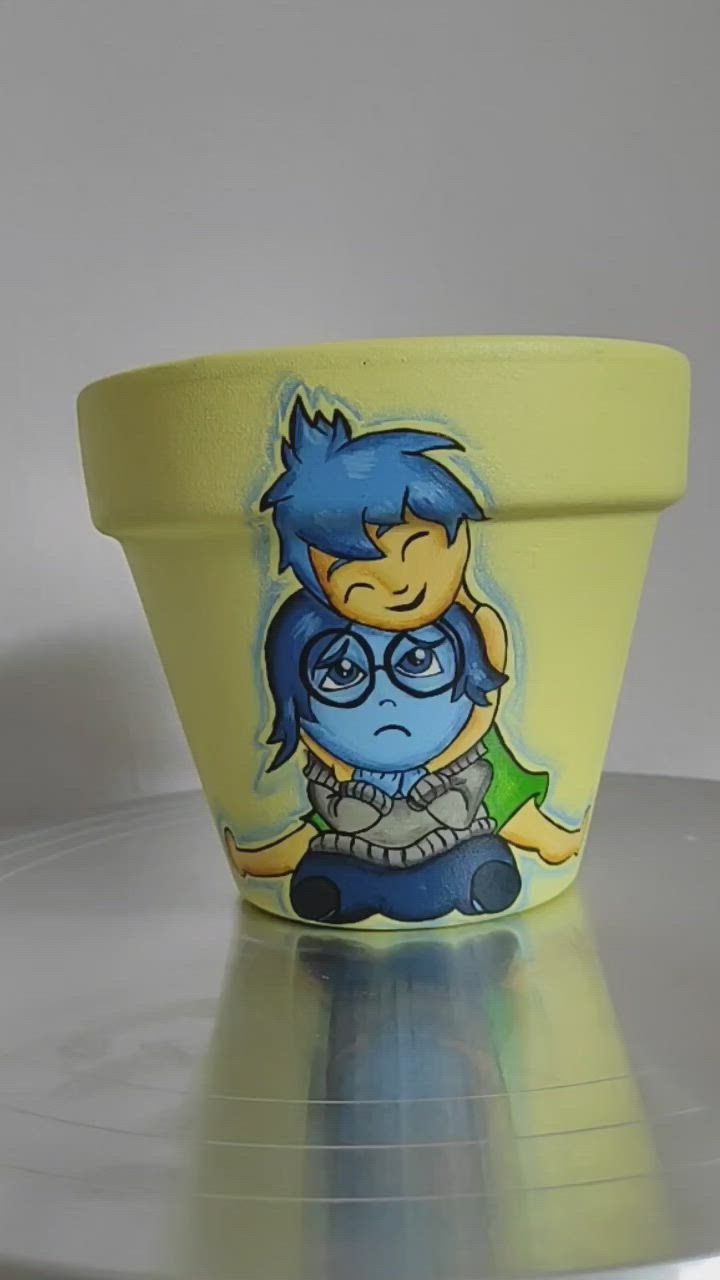 This may contain: a yellow flower pot with a cartoon character painted on it