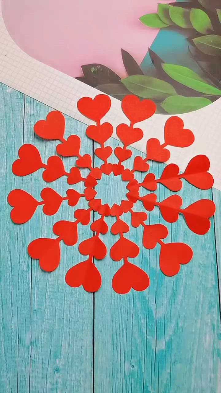 This may contain: paper hearts are arranged in the shape of a heart on a piece of wood with scissors