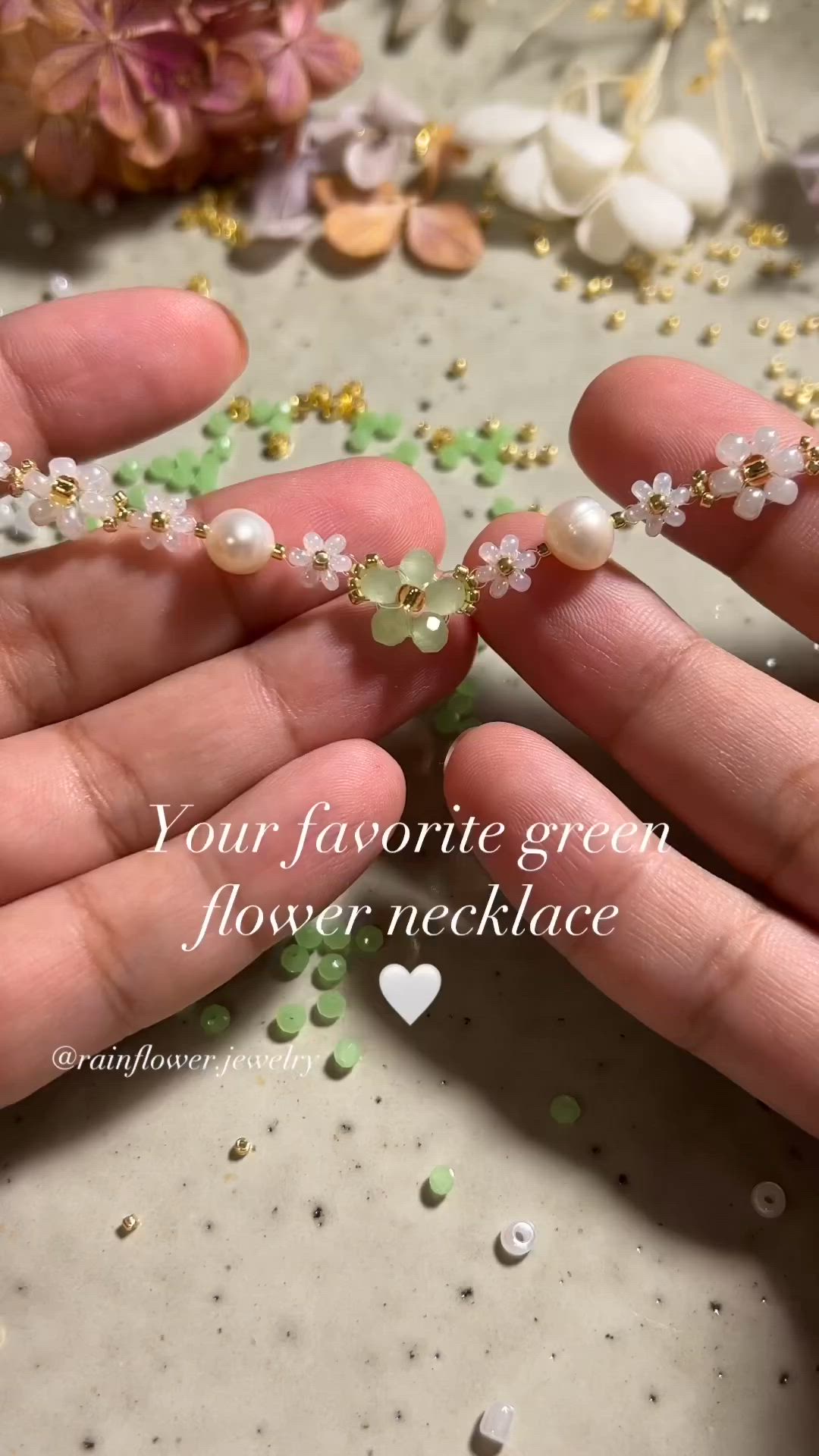 This may contain: two hands are holding pearls and flowers in their palm, with the words you're favorite green flower necklace