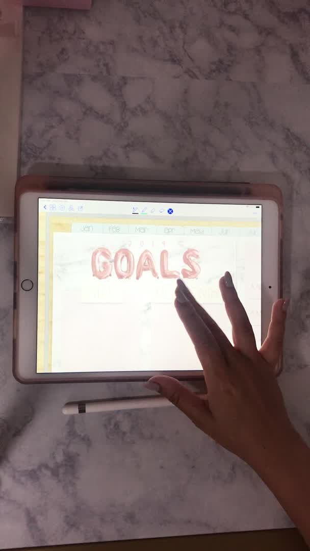 This may contain: a person using an ipad with the word goals written on it in front of them