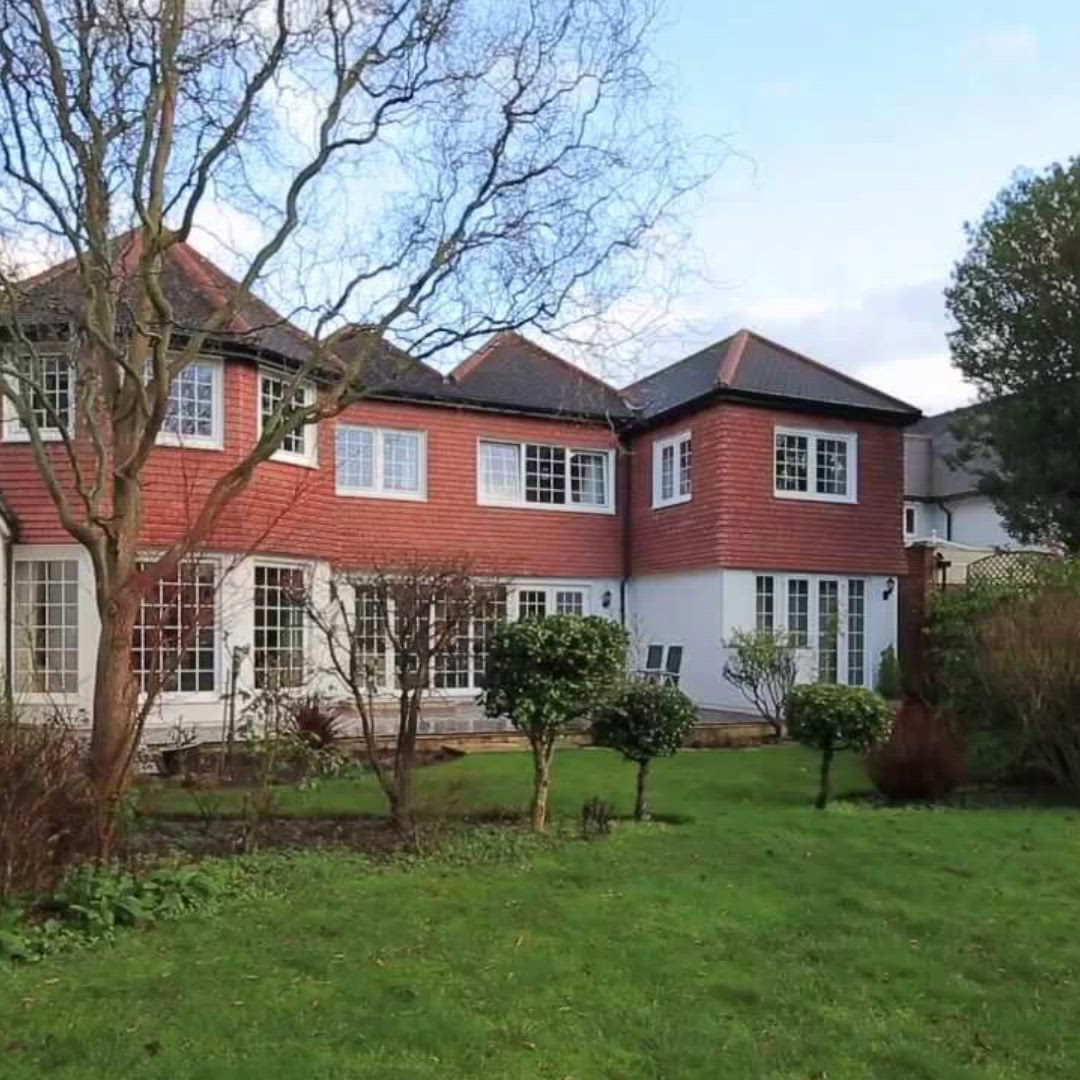 This may contain: a large red brick house sitting on top of a lush green field next to trees