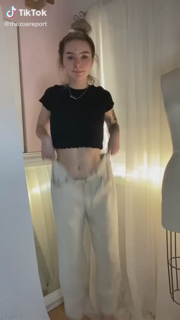 This may contain: a woman is showing off her stomach and wearing white pants with an attached chain around her waist