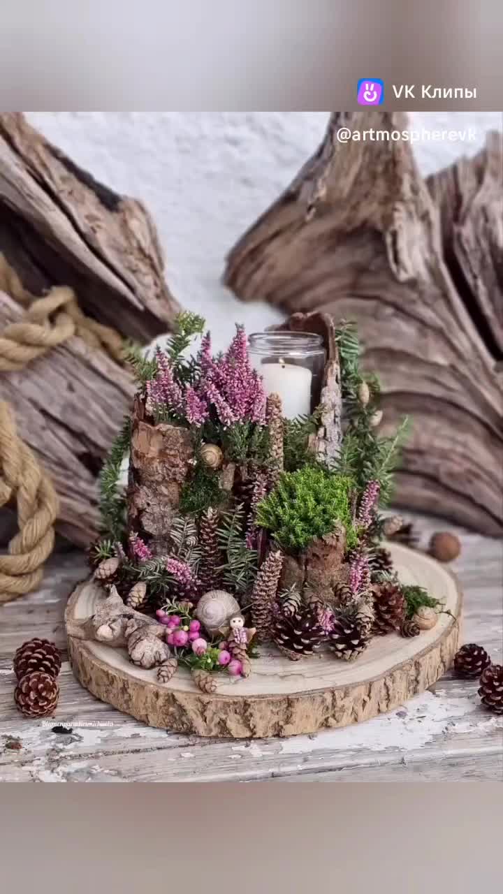 This may contain: a candle is sitting on a piece of wood with flowers and pine cones around it