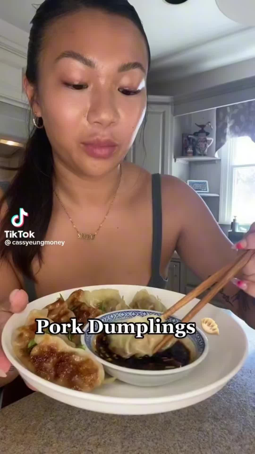 This may contain: the woman is eating dumplings with chopsticks