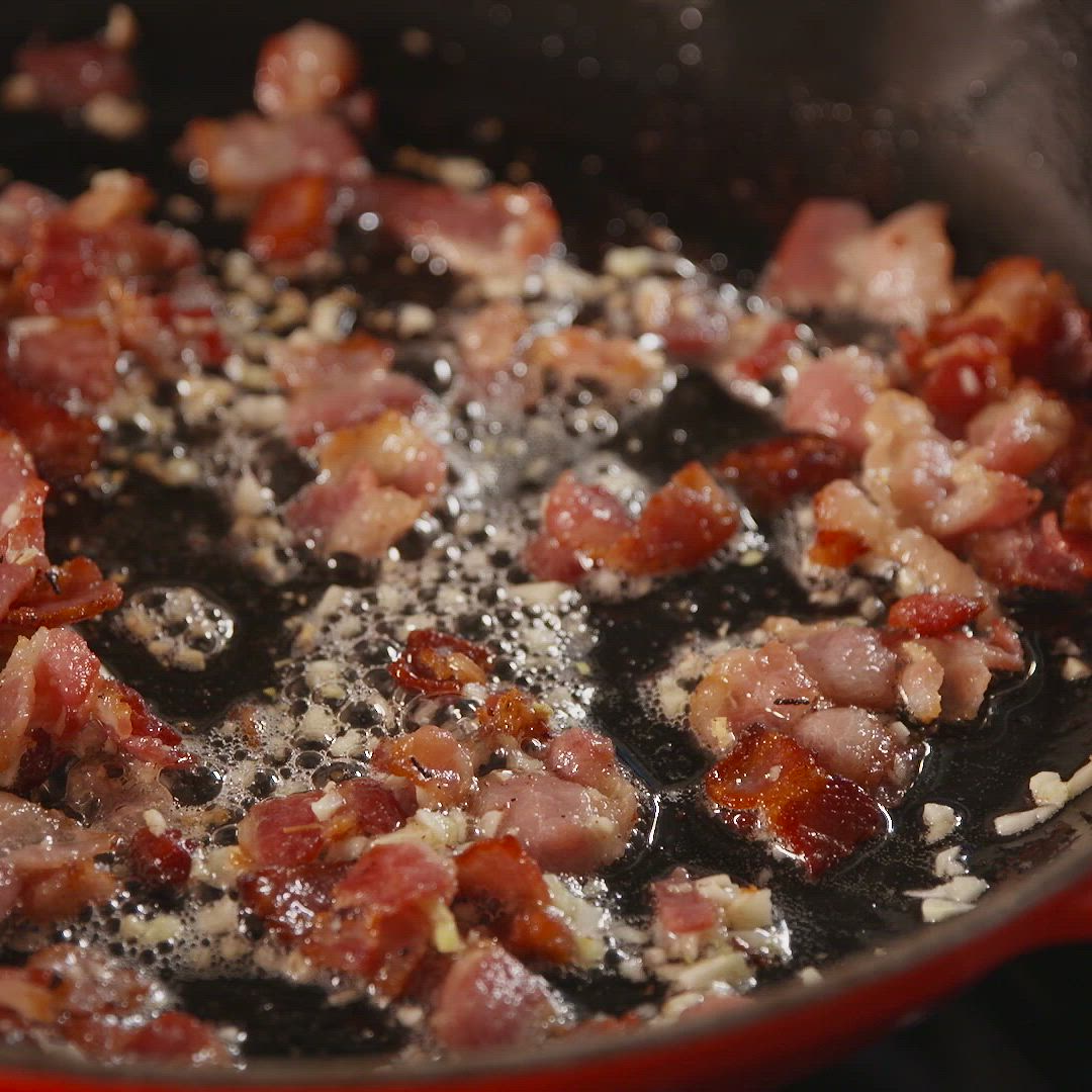 This may contain: someone is holding a fork full of spaghetti with bacon and parmesan cheese on it