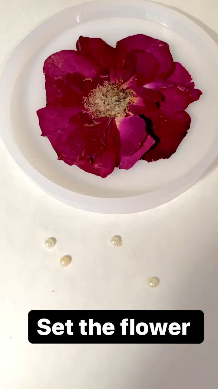 This may contain: a white plate topped with a pink flower covered in gold flakes