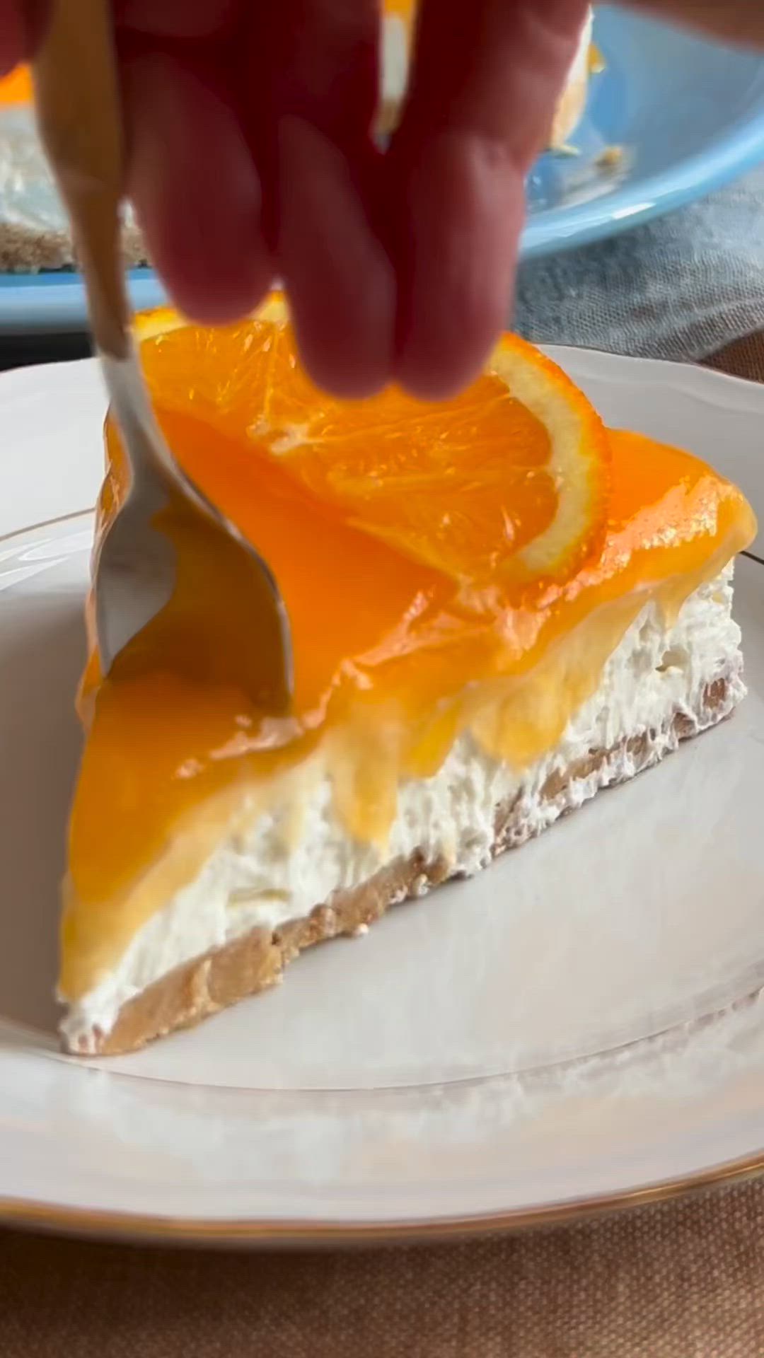 This may contain: a person cutting into a slice of cheesecake with oranges on top and white frosting