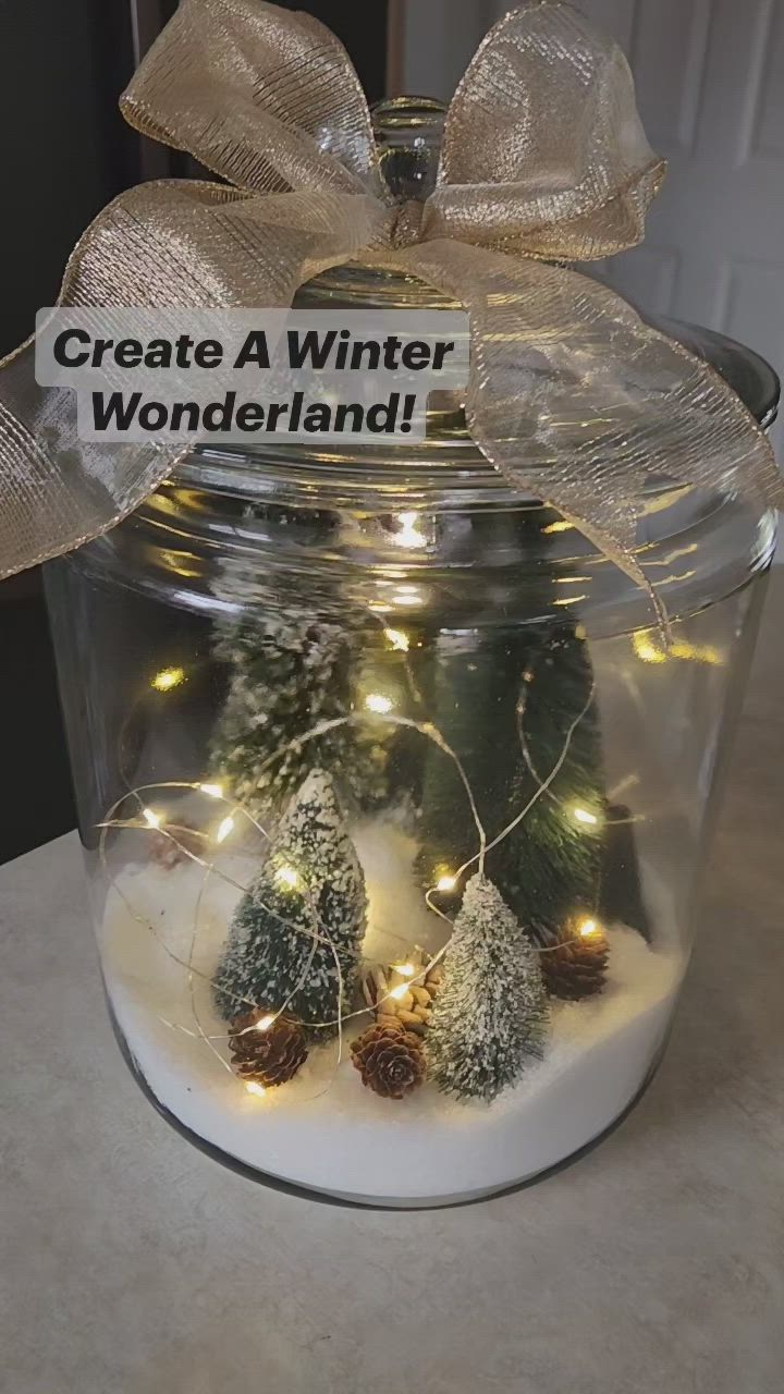 This may contain: a glass jar filled with fake trees and lights that says create a winter wonderland on it