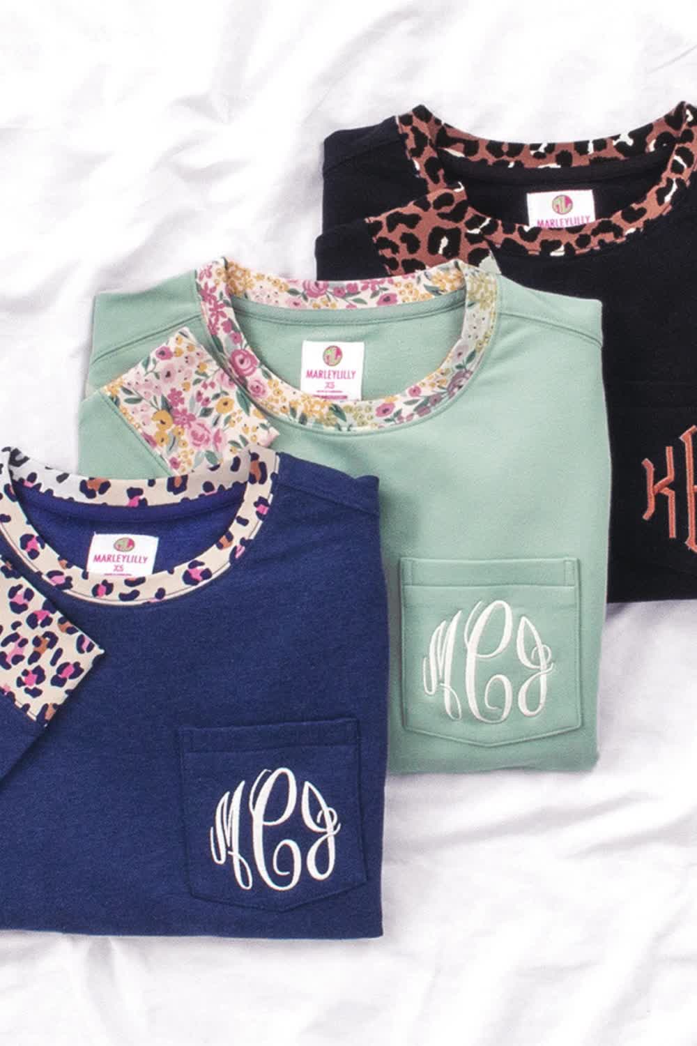 This Monogrammed Pattern Trim Sweatshirt will be your new favorite piece in your closet this fall. This trendy crewneck sweatshirt features a personalized faux pocket, side slits at the hem, and a pattern accent design on the collar and sleeves. Available in sage, navy, and black; you can personalize your crewneck with the font of your choice.