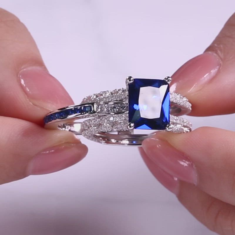 This may contain: a woman's hand holding an engagement ring with blue and white stones on it