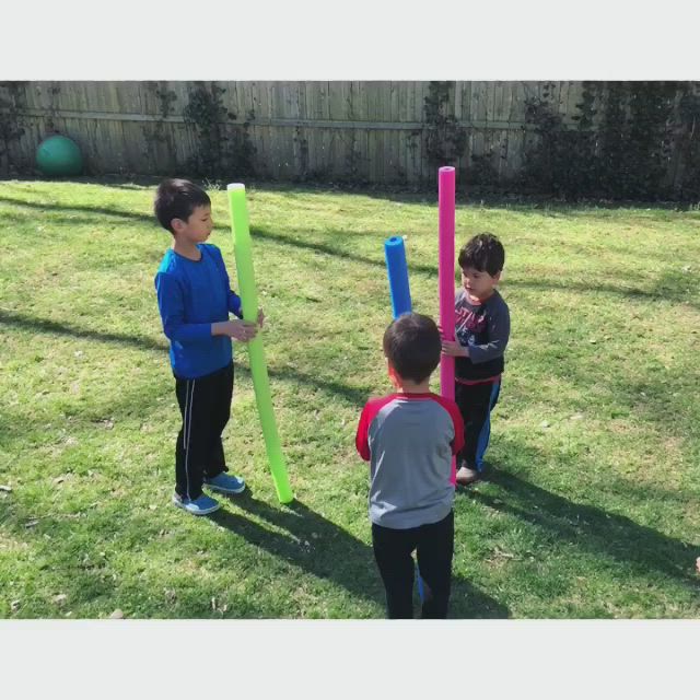 This may contain: three young boys playing with plastic toys in the yard, one boy is holding a bat and two others are looking at it