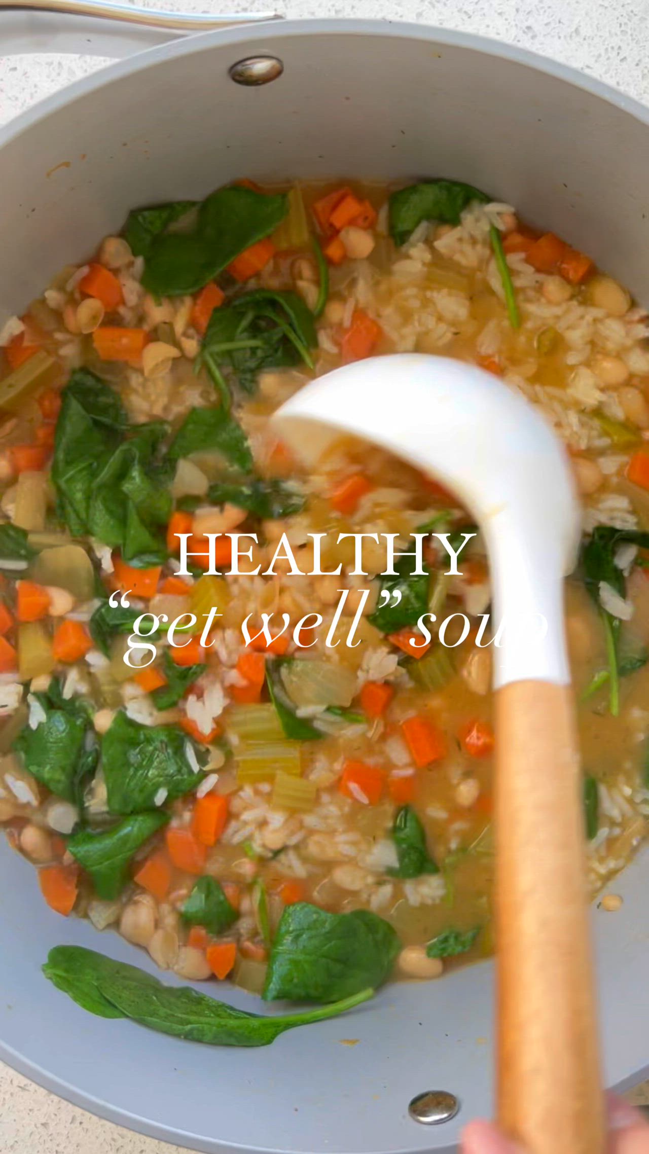 This may contain: a white bowl filled with vegetables and rice next to a wooden spoon on top of a table