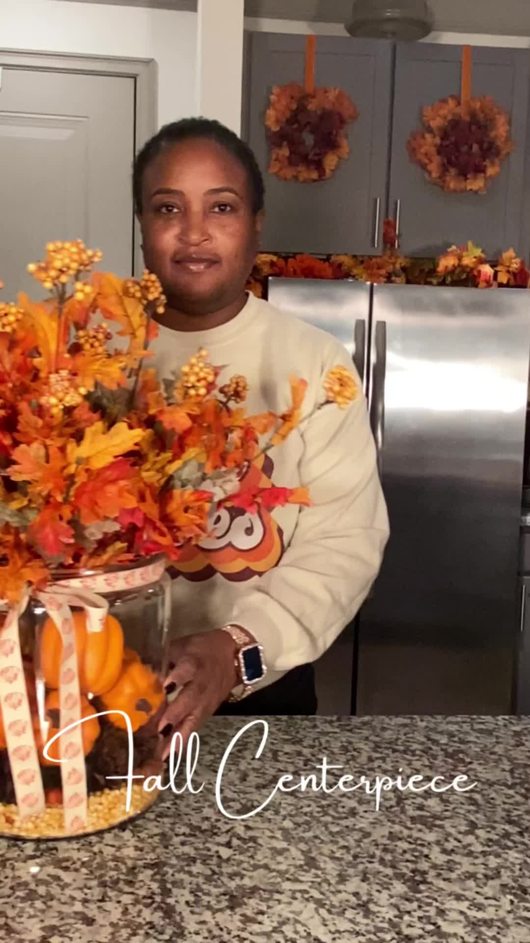 This may contain: a woman standing in front of a kitchen counter holding a vase filled with orange flowers