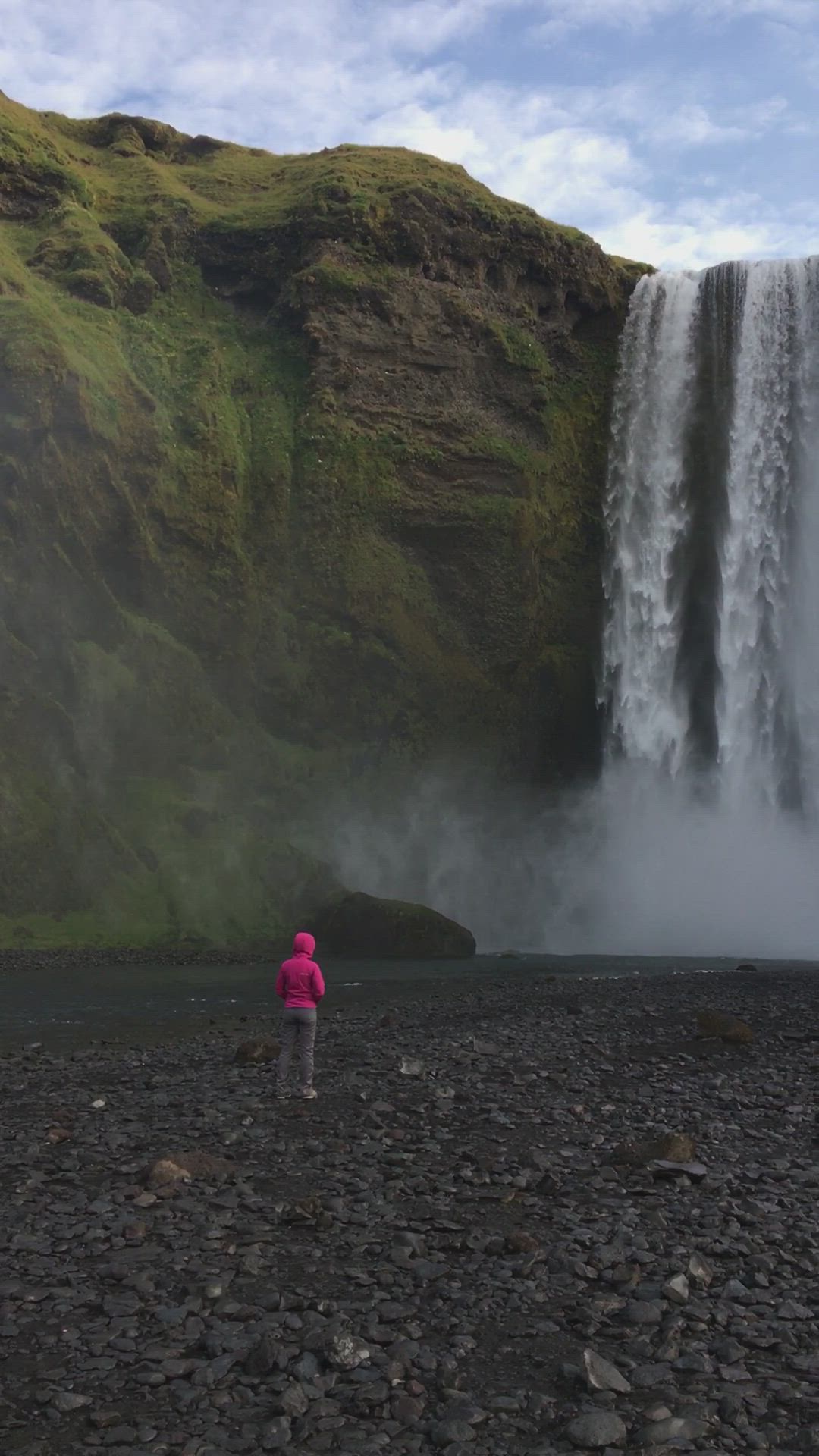 This may contain: a person standing in front of a waterfall