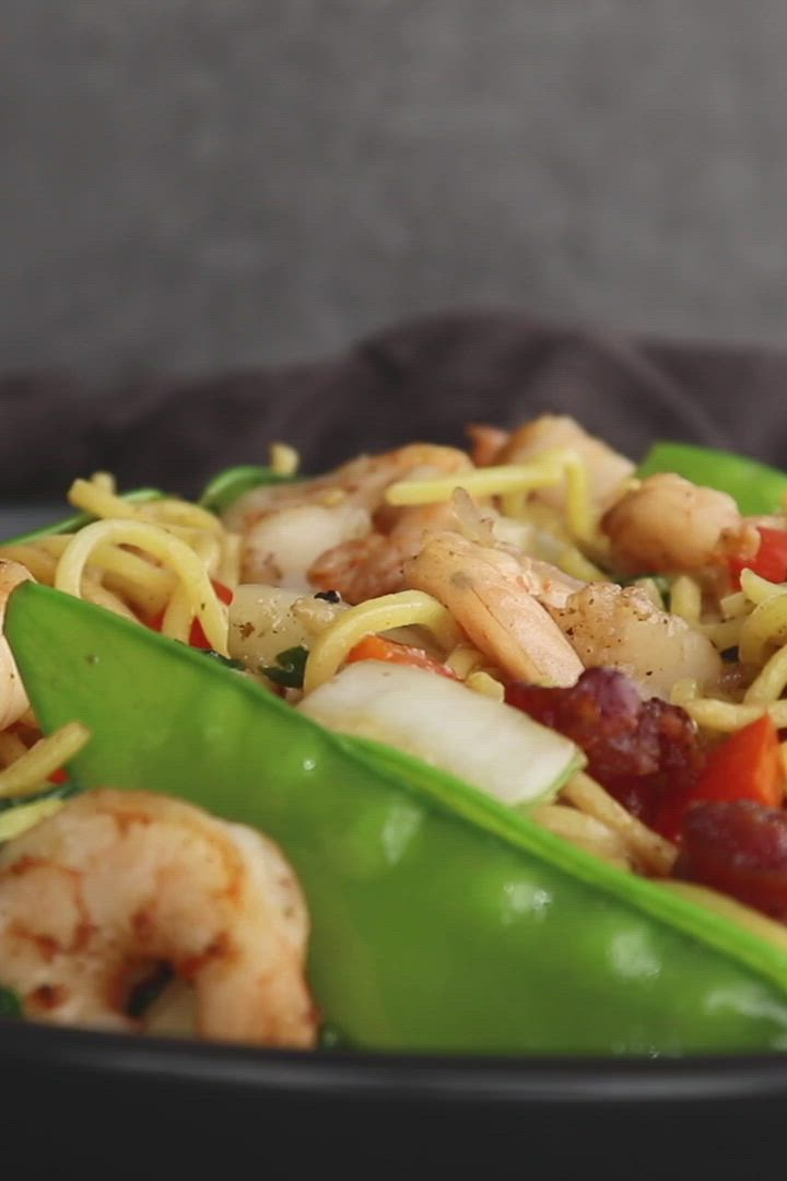 This may contain: a close up of a plate of food with shrimp, noodles and vegetables on it