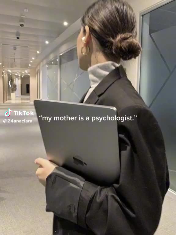 This may contain: a woman holding a laptop computer in an office building with the caption'my mother is a psychicist '