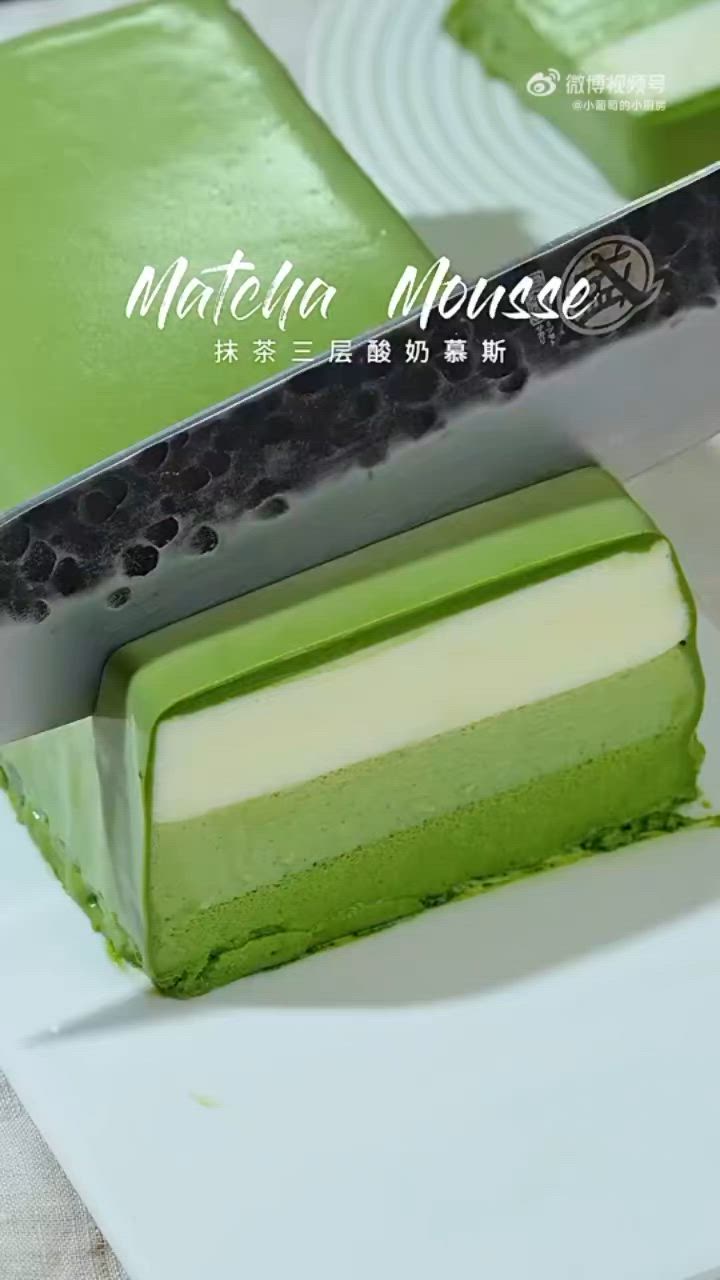 This may contain: there is a green cake with a knife on the cutting board and it has white frosting