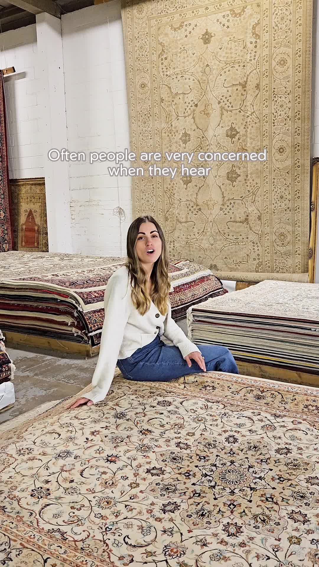 This may contain: a woman sitting on the ground in front of rugs