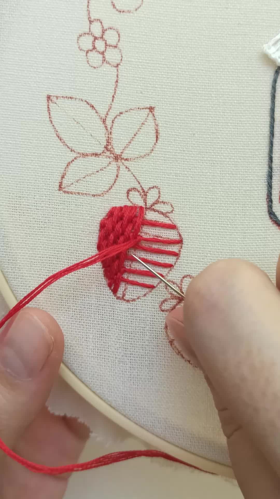 This may contain: someone is stitching something on a piece of fabric with red thread and scissors in front of them