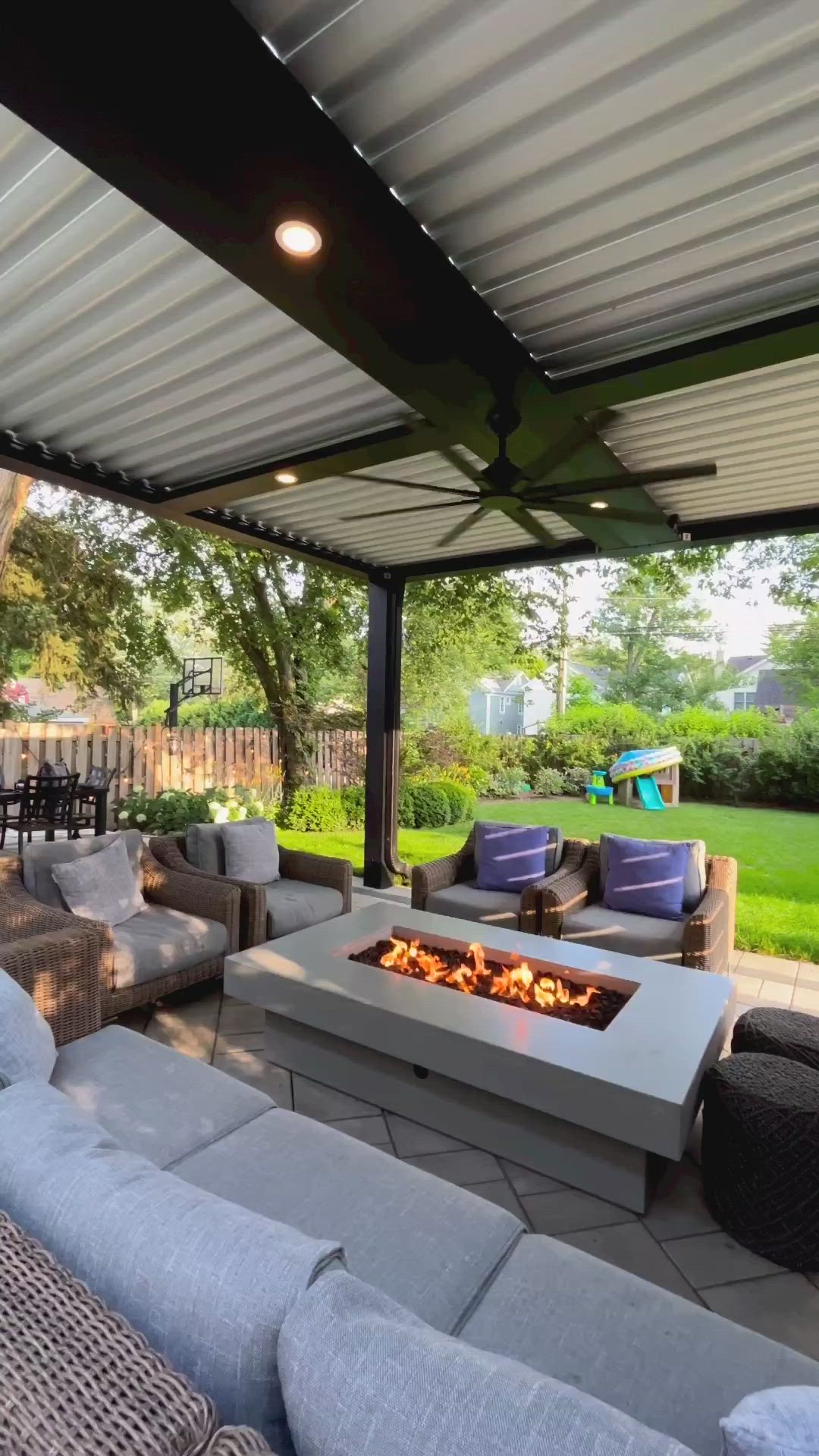 This may contain: an outdoor living area with couches, tables and fire pit in the middle of it