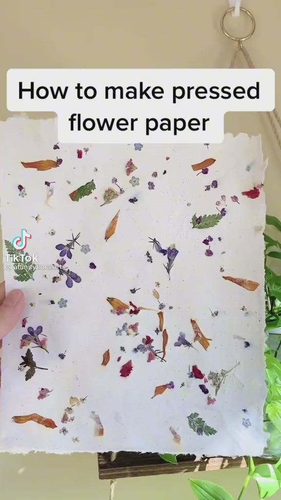 This may contain: a person holding up a piece of paper with flowers on it and the words how to make pressed flower paper