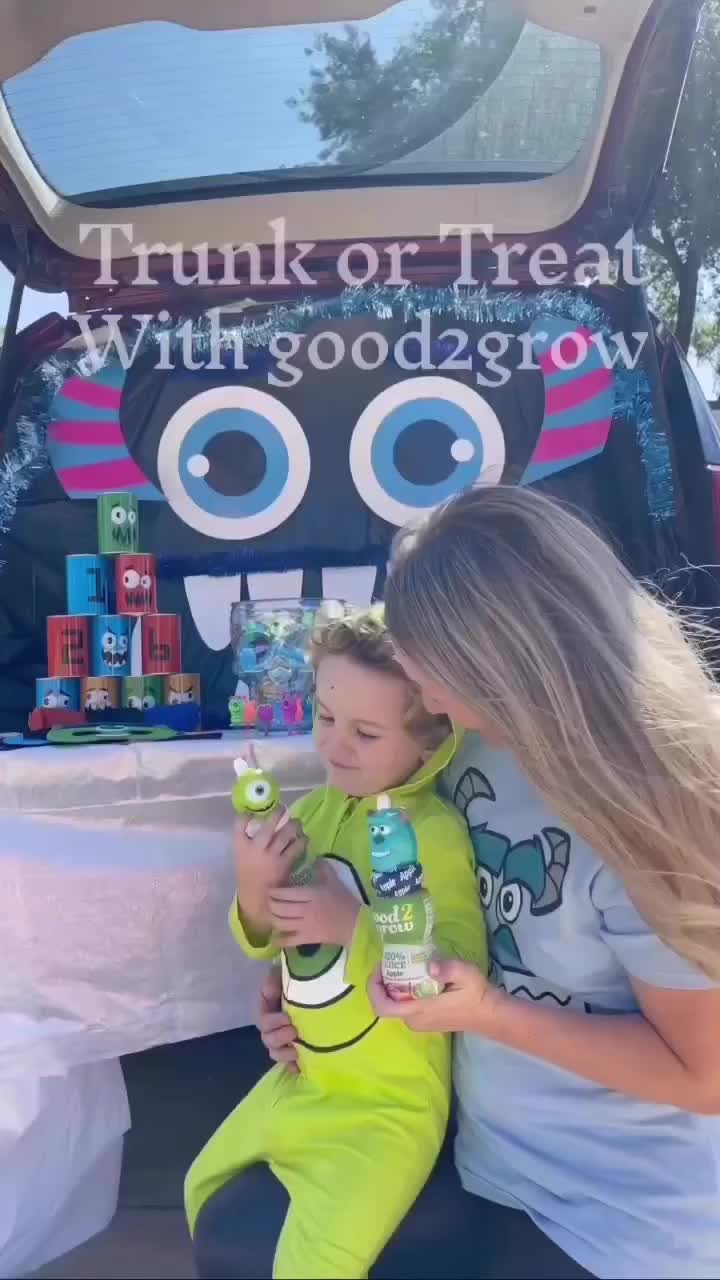 This may contain: a woman and child sitting in front of a trunk or treat sign