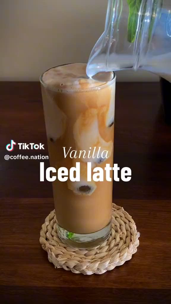 This may contain: an iced latte is being poured into a glass with ice and garnishes