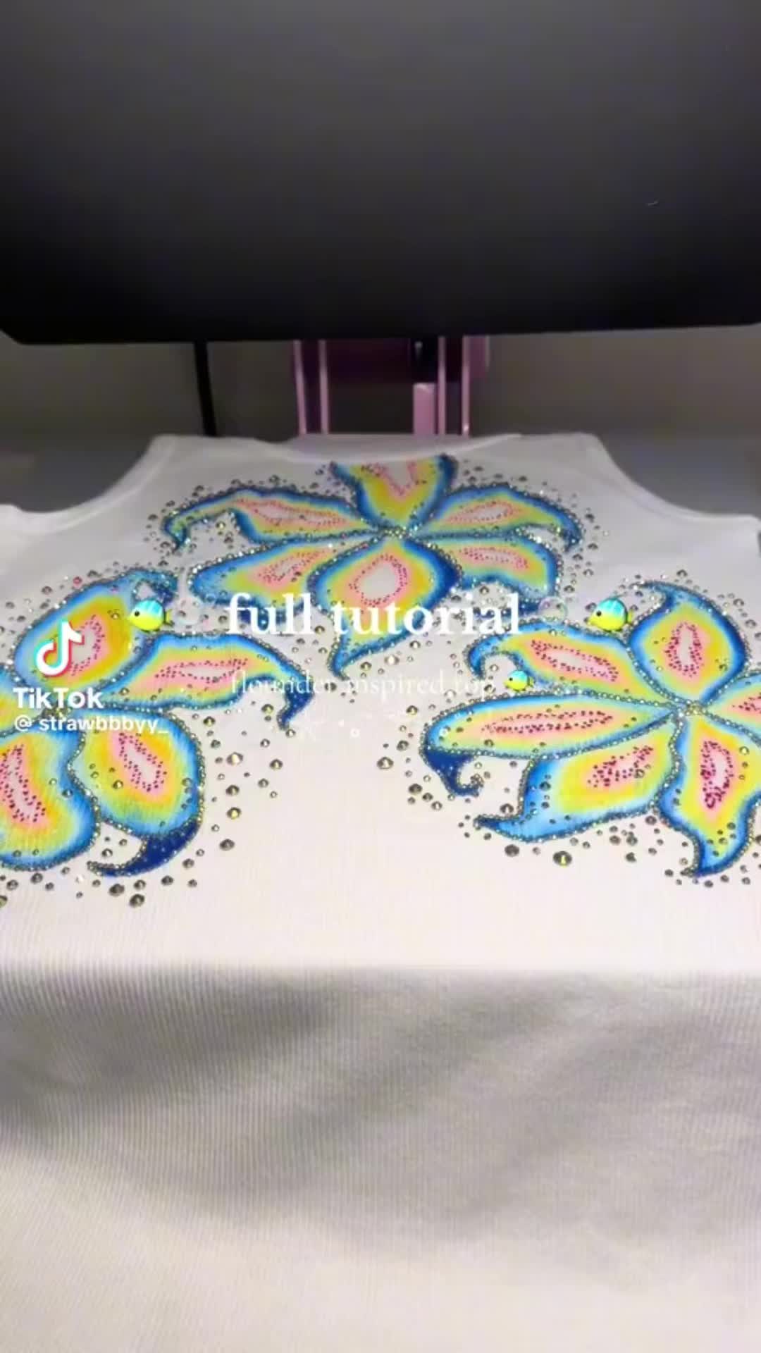 This may contain: the back of a white shirt with blue and yellow flowers on it, next to a sewing machine