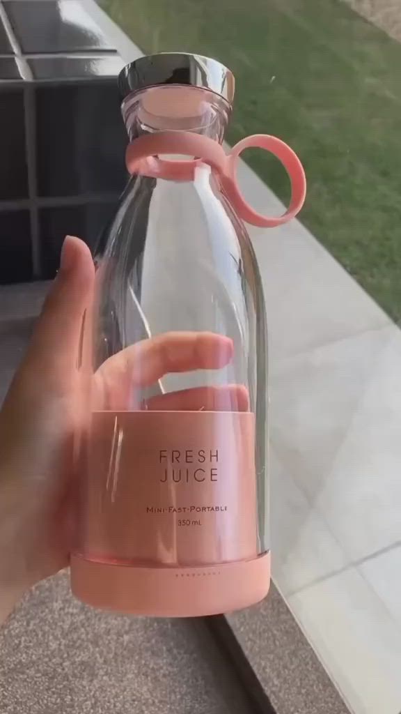 This may contain: a person holding up a glass bottle with a pink ribbon on the top that says fresh juice