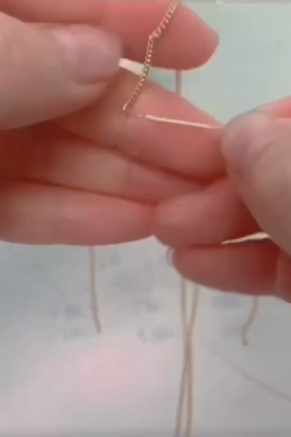 This may contain: a person holding a piece of wire with the words handmade pearl necklace