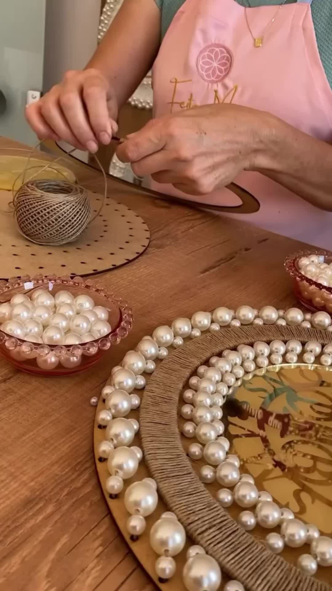 This may contain: a woman in an apron is working on some crafts with pearls and beads around her