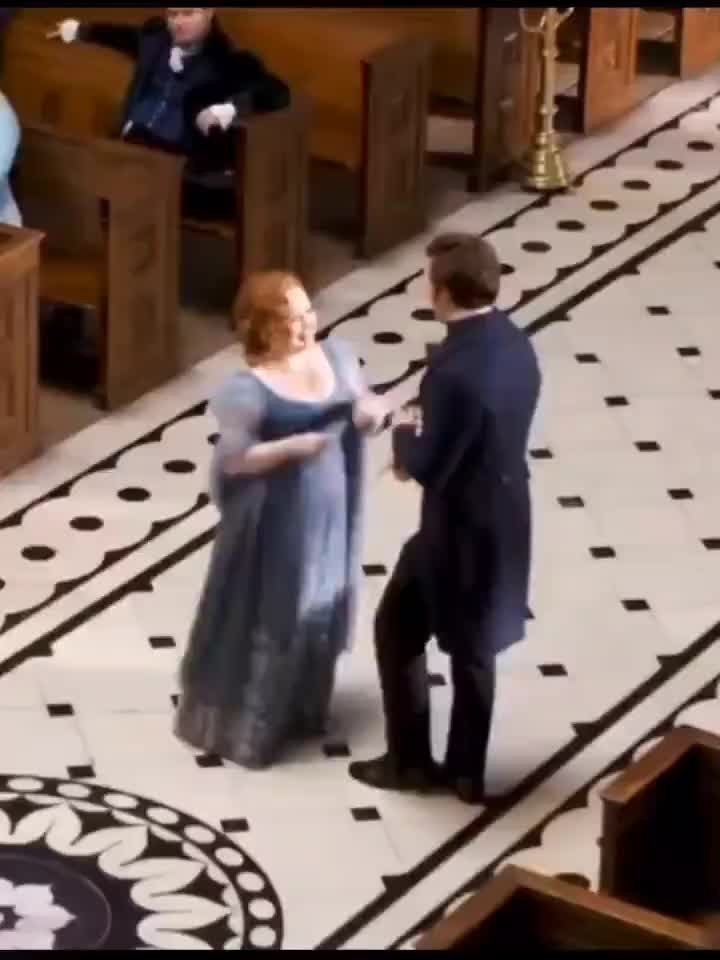 This may contain: a woman in a blue dress standing next to a man