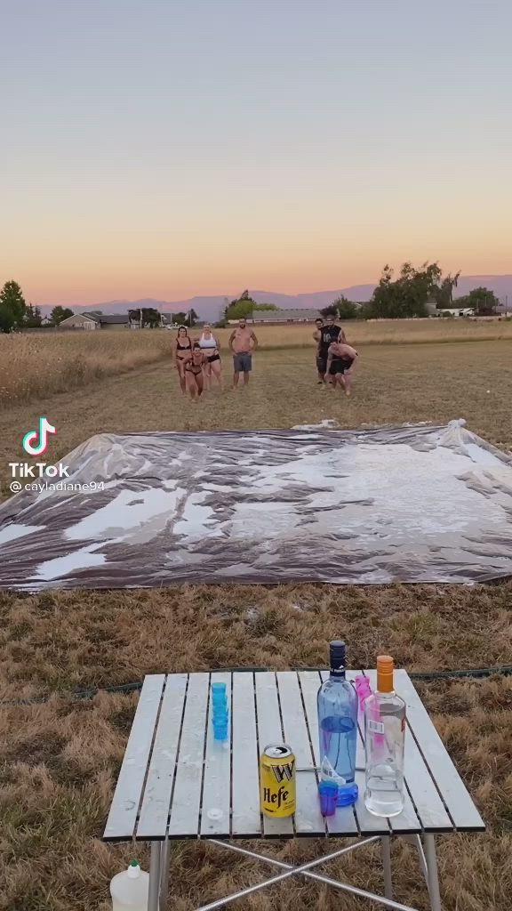 This may contain: there is a picnic table with drinks on it in the middle of an open field