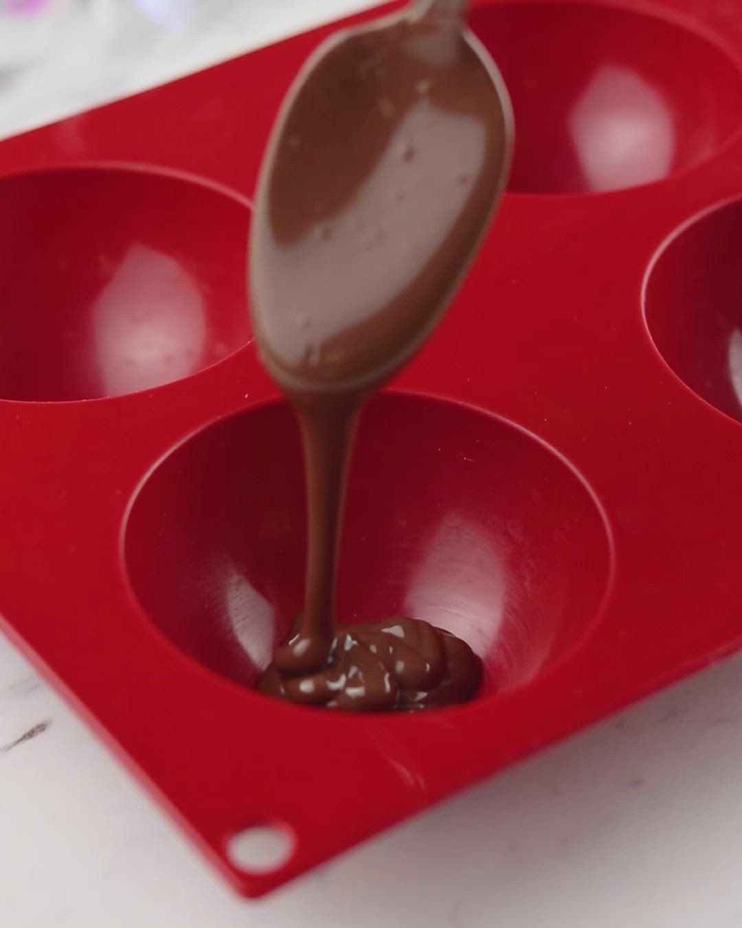 This may contain: a spoon with chocolate sauce in it is being dipped into the cupcake pans