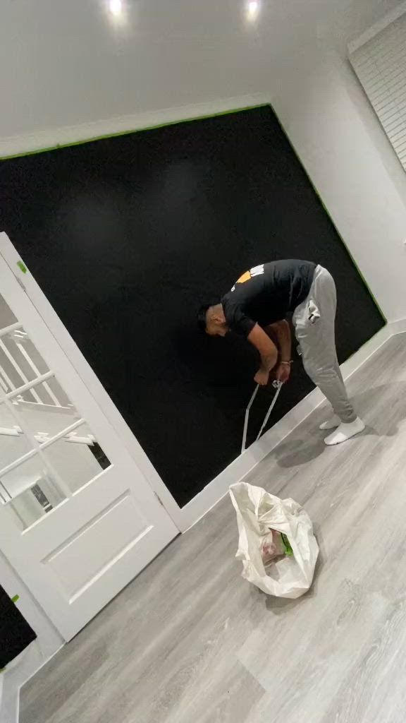 This may contain: a man standing on top of a hard wood floor in front of a black wall