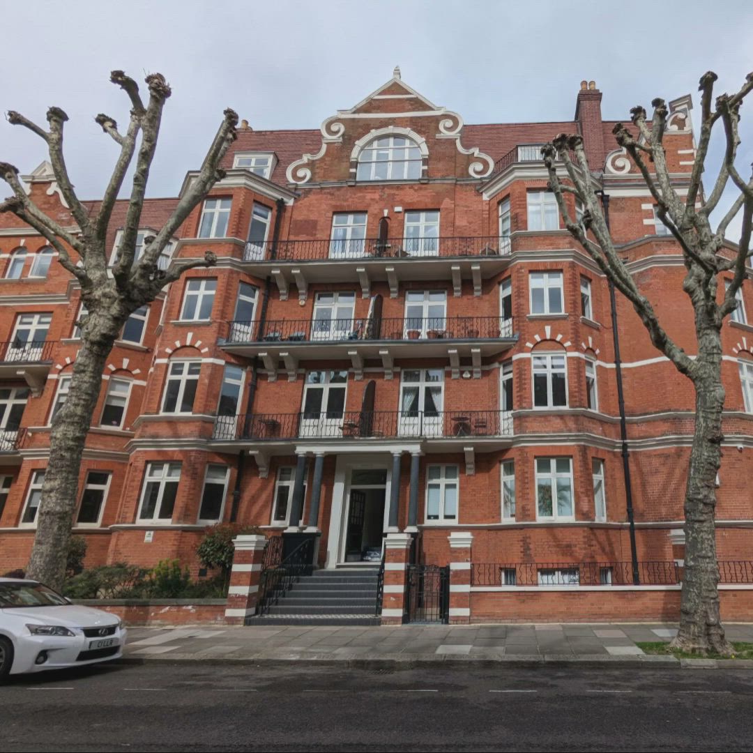 This may contain: an old brick building with many windows and balconies on the top floor, next to a car parked in front of it