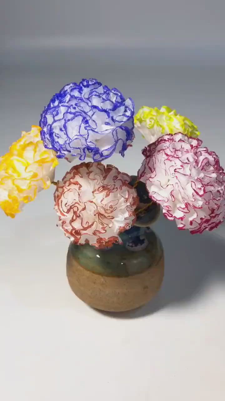 This may contain: four different colored flowers in a small vase