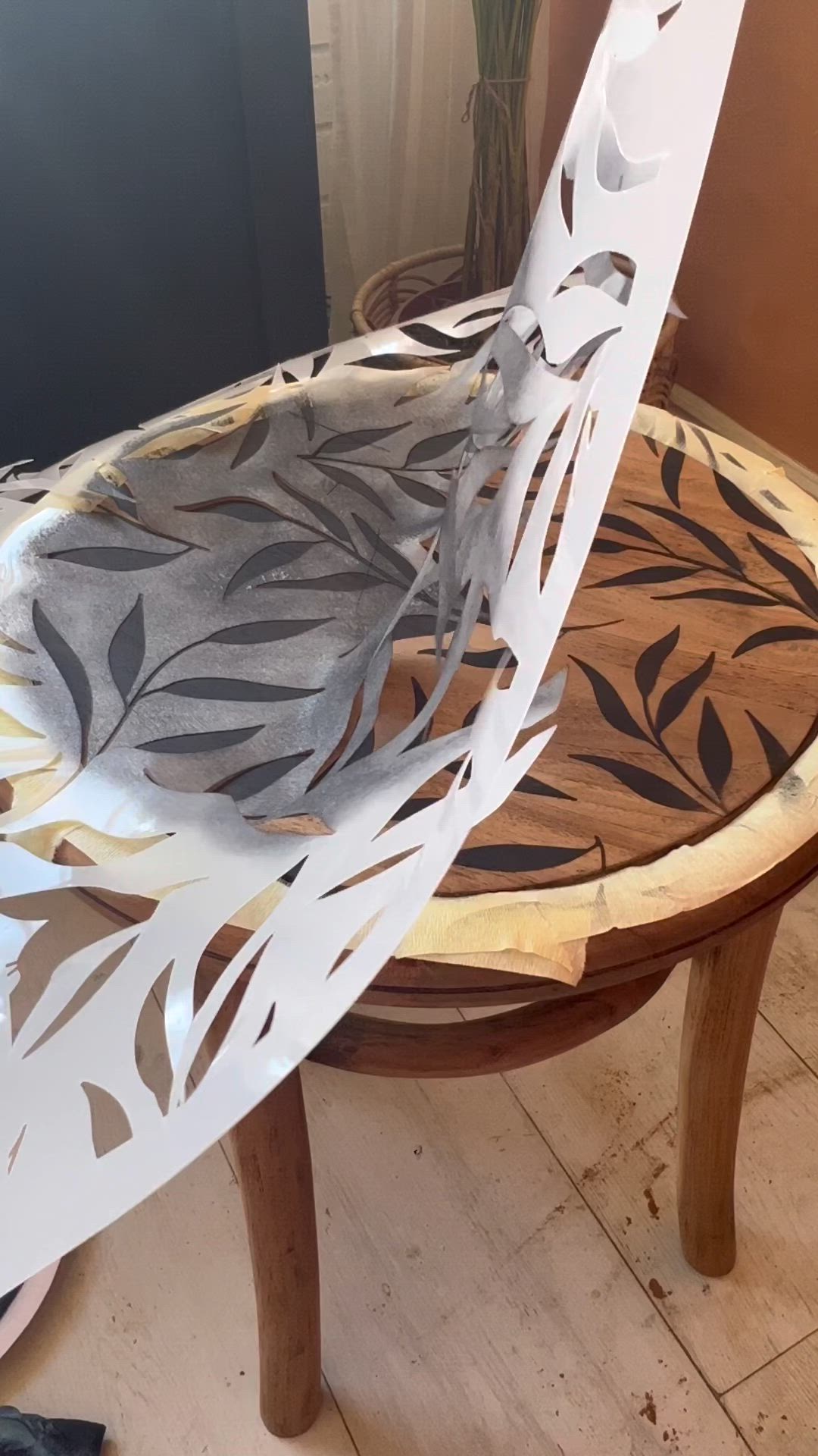 This may contain: a round wooden table with leaves painted on it