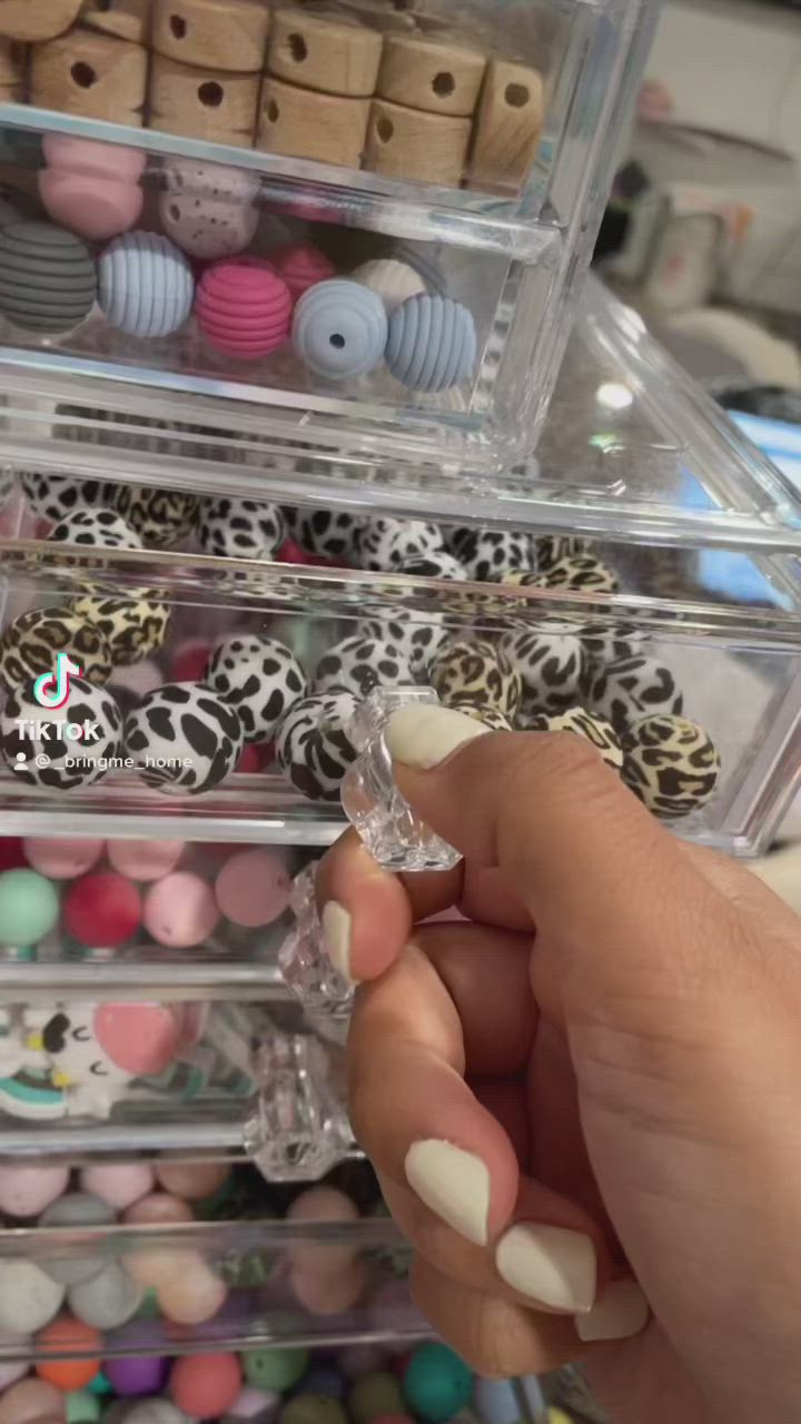 This may contain: a bracelet with pink, white and black beads on top of a wooden table next to a key