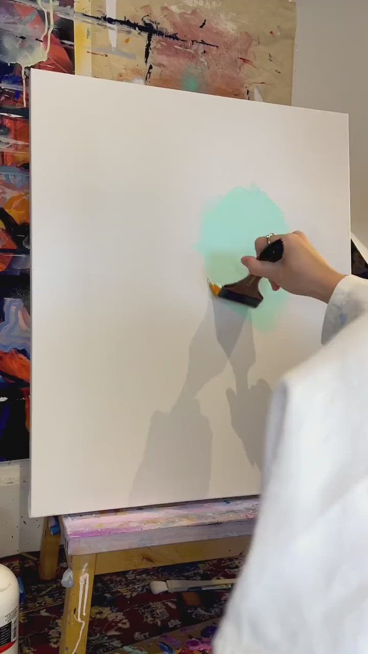 This may contain: a person is using a brush to paint on a large white piece of art work