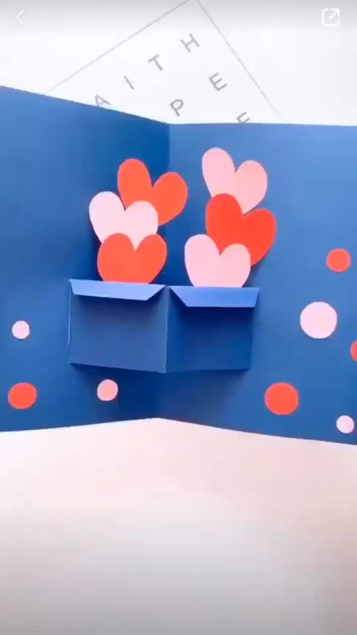 This may contain: someone is cutting out some paper hearts on a blue background with red and pink dots