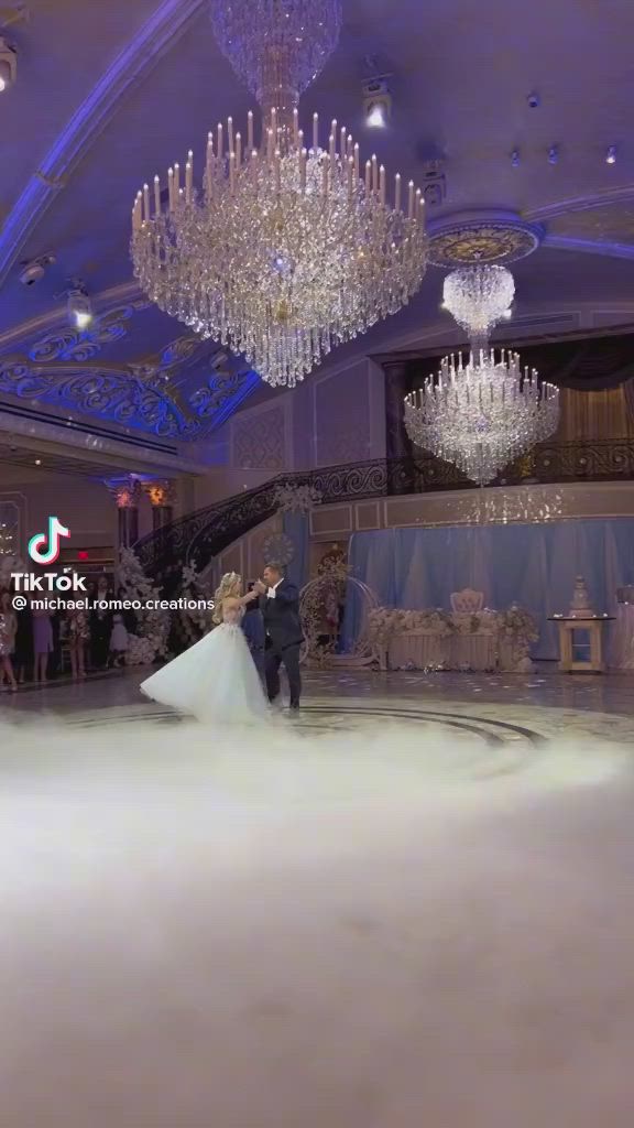 This may contain: the bride and groom are standing in front of chandeliers