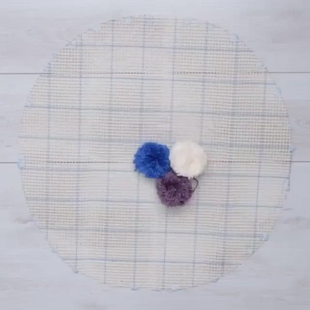 This may contain: a piece of cloth with two different colored pom poms on top of it